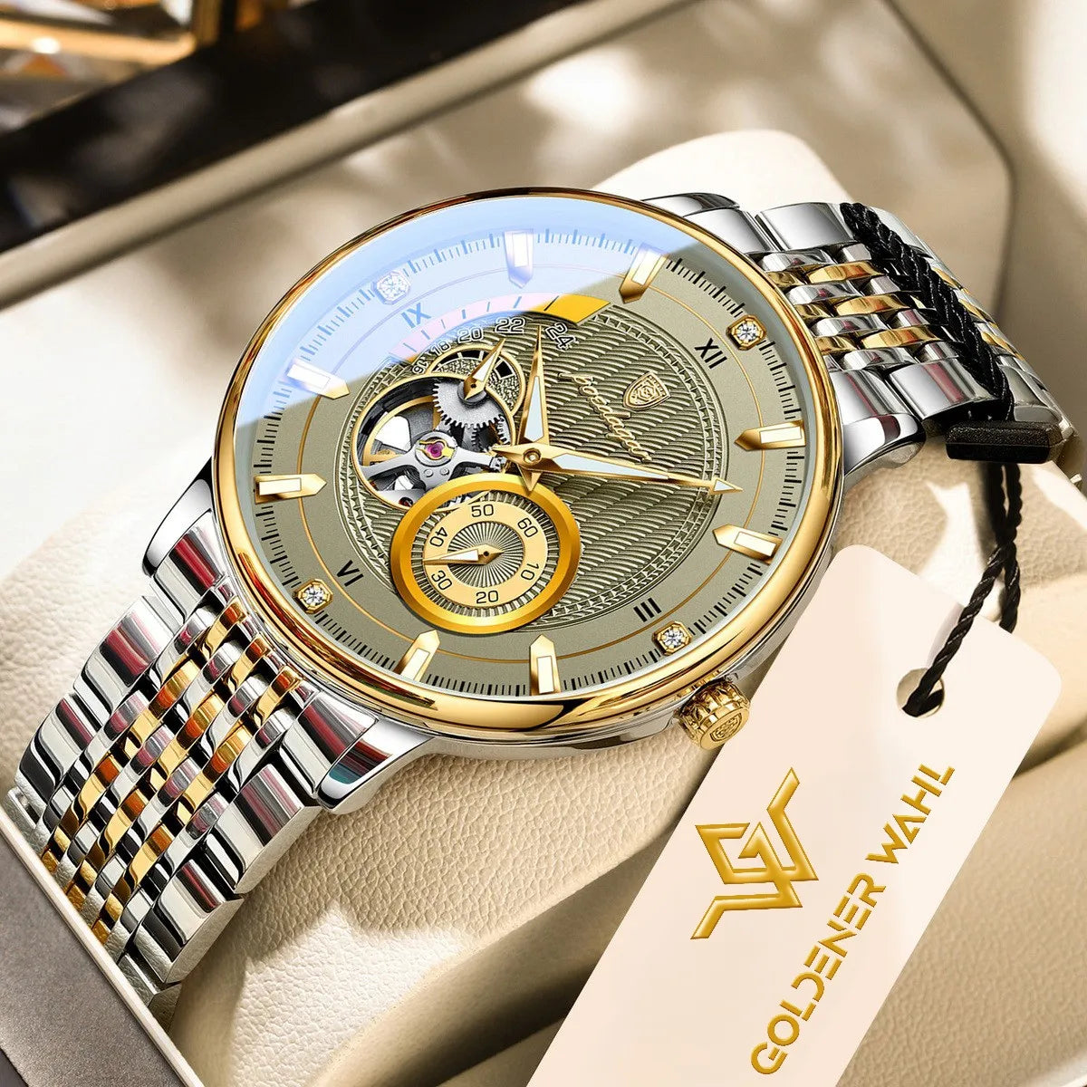 A Goldener Wahl mechanical watch with a silver and gold-tone stainless steel link bracelet, featuring an open dial with a skeletonized center and a gold subdial. The watch is displayed on a beige leather watch cushion with its branded hangtag attached.