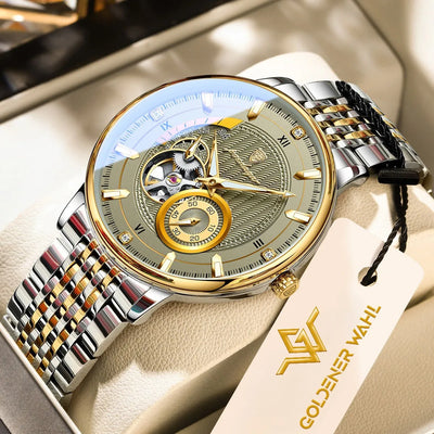 A Goldener Wahl mechanical watch with a silver and gold-tone stainless steel link bracelet, featuring an open dial with a skeletonized center and a gold subdial. The watch is displayed on a beige leather watch cushion with its branded hangtag attached.
