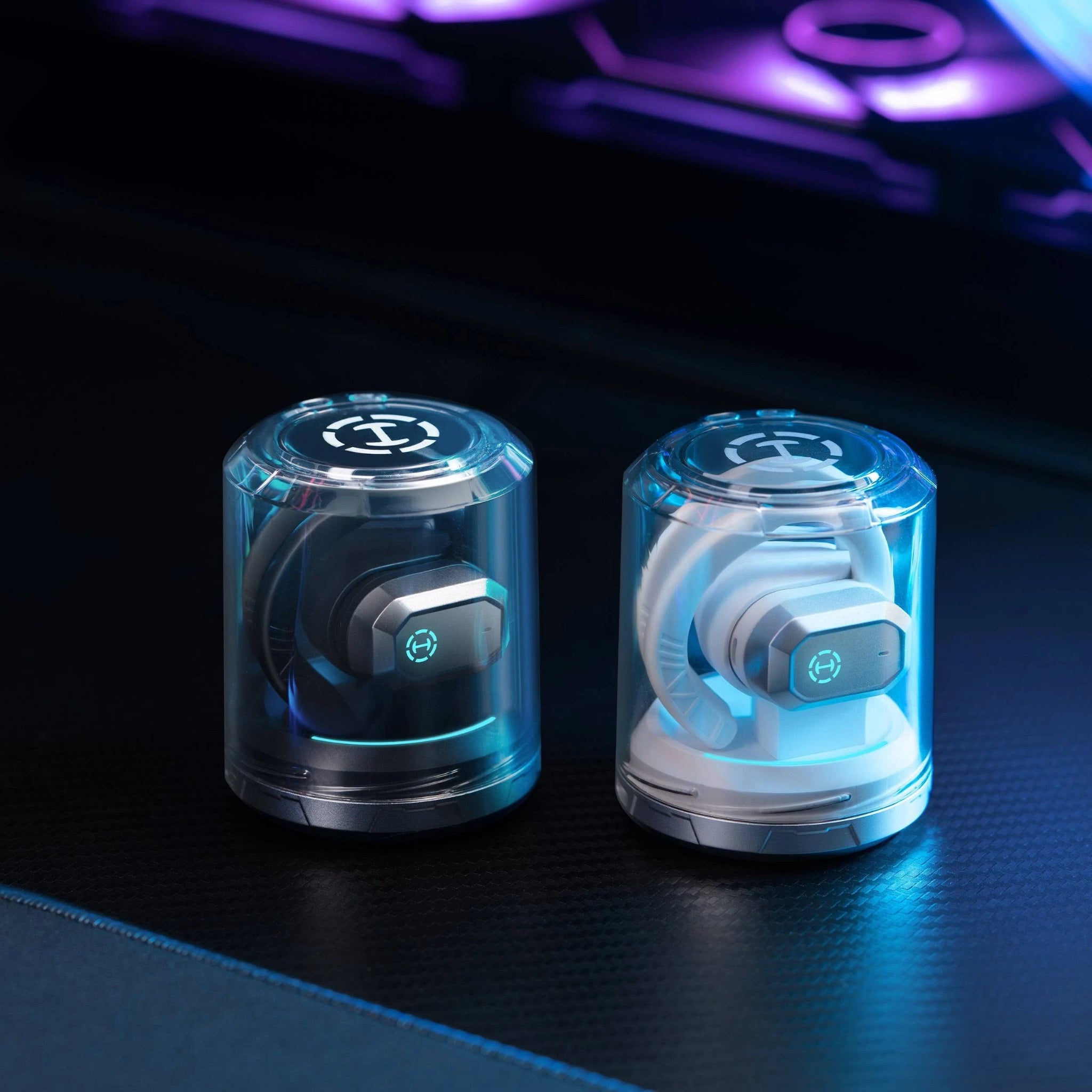 Two transparent cylindrical devices with electronic components on a dark surface.
